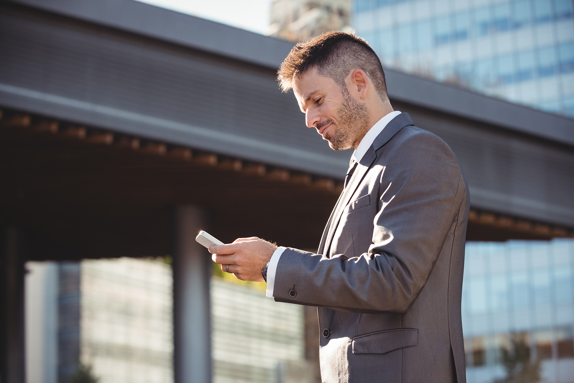 Businessman using mobile phone near office building